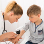 Doctor Examining Skin Of Little Boy