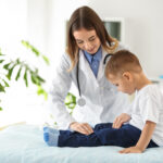 Female doctor working with cute little boy in clinic